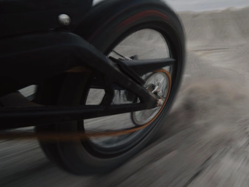 Das Hinterrad einer E Ride Pro in voller Fahrt beim beschleunigen auf losem Erd- oder Kies-Boden.